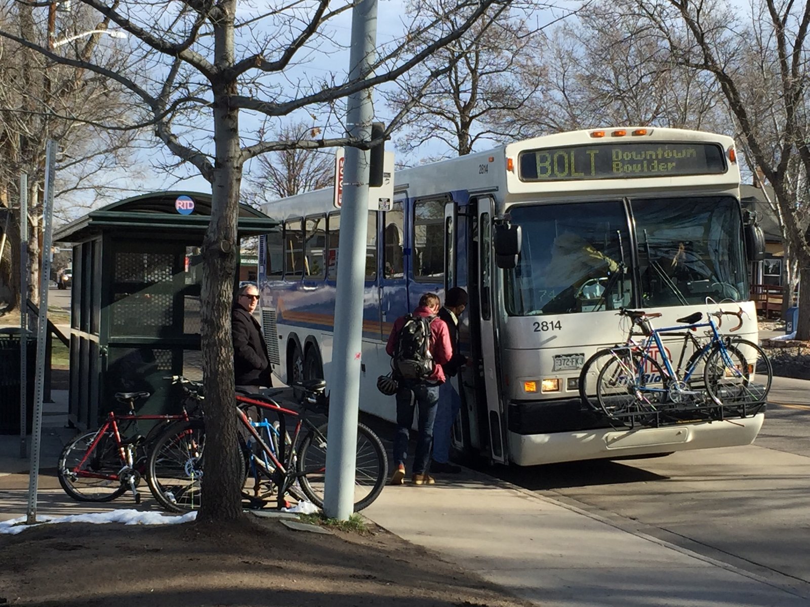 Someone waiting to board a bus with bikes on the front