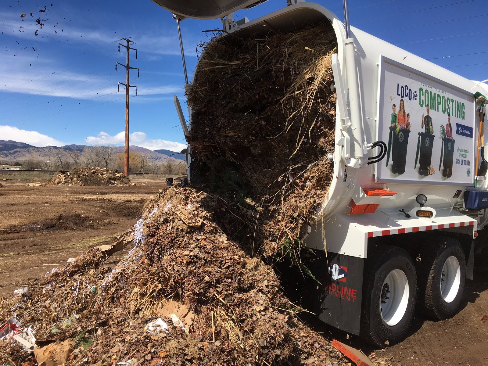 A truck dumping compost onto a field.