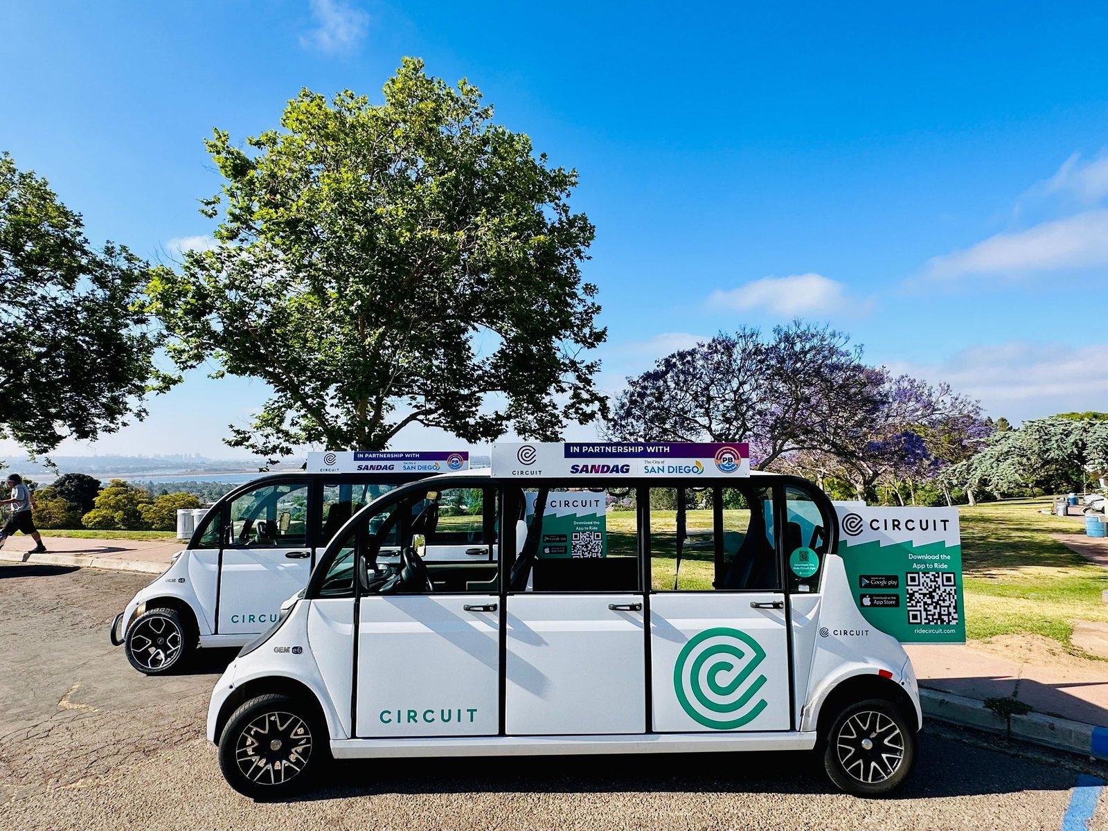 Electric shuttles parked in front of a park